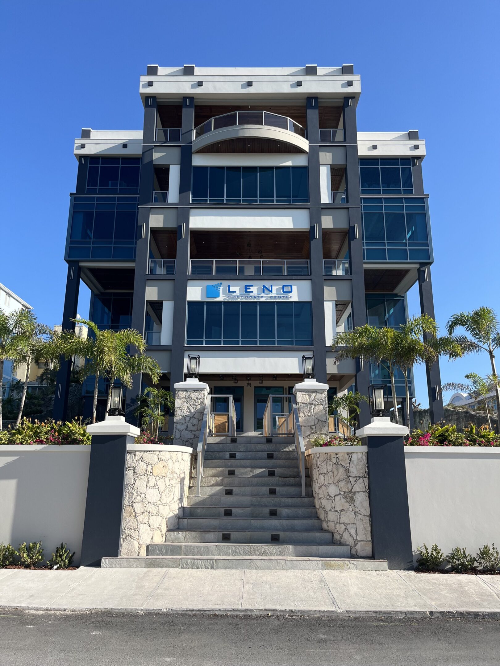 Modern multi-story building with glass balconies and palm trees.