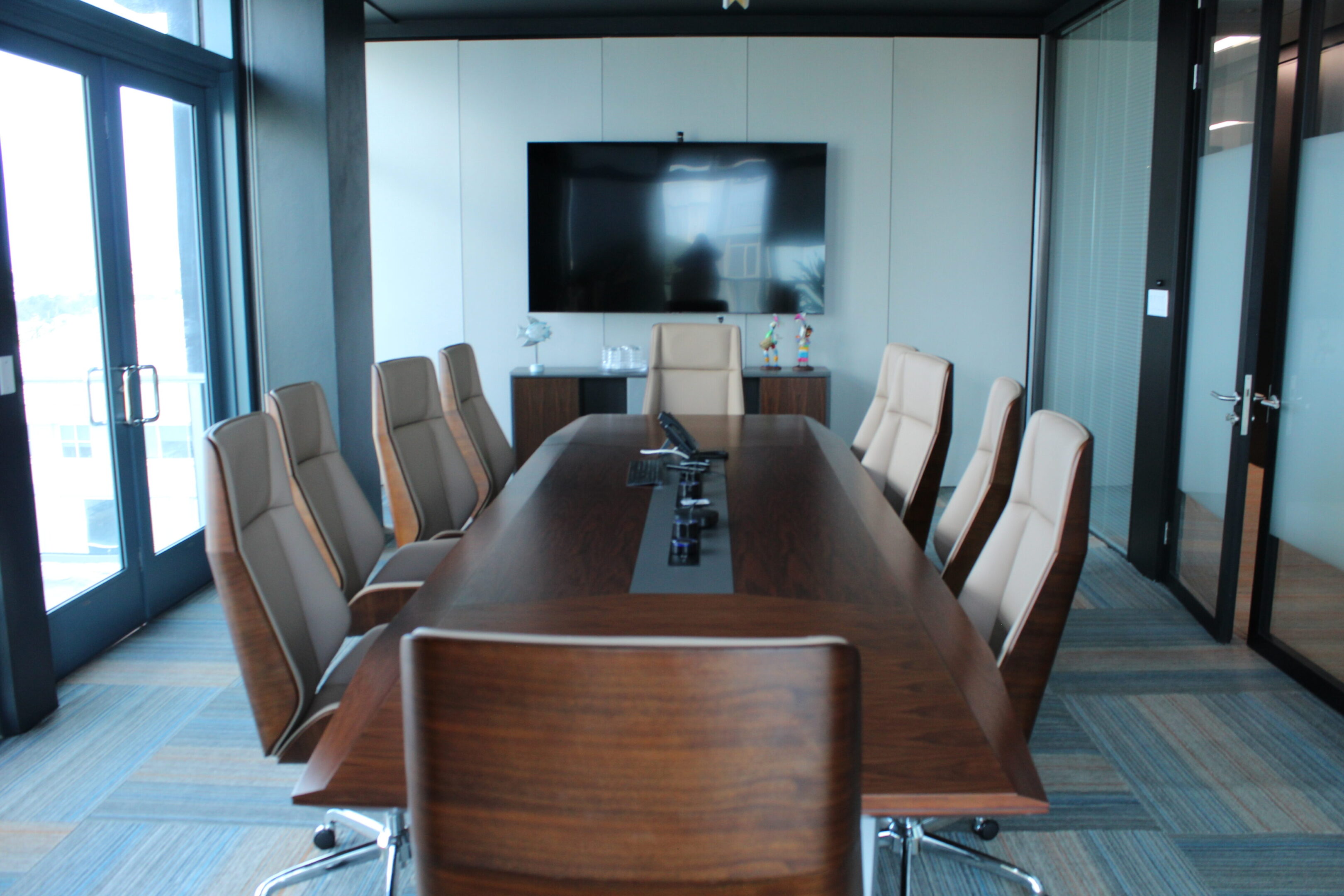 Modern conference room with a long wooden table and leather chairs.