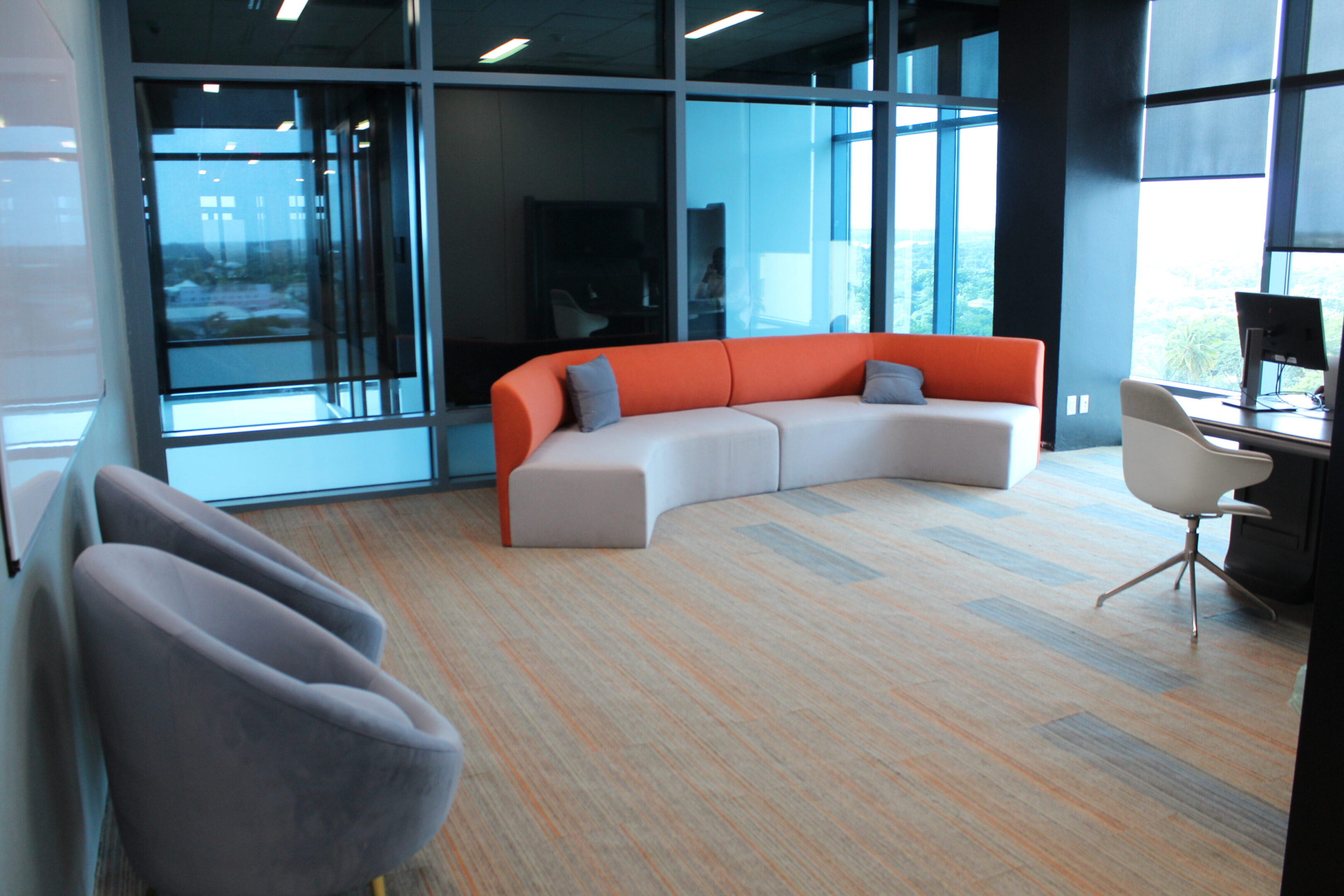Modern office lounge with curved orange and gray seating.