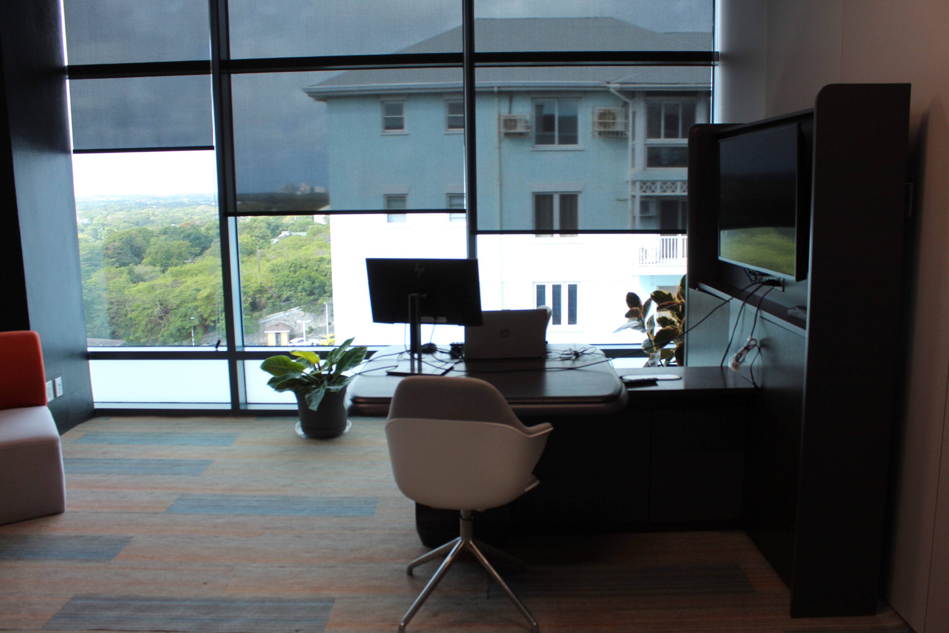 Modern office workspace with a computer and ergonomic chair by large windows.