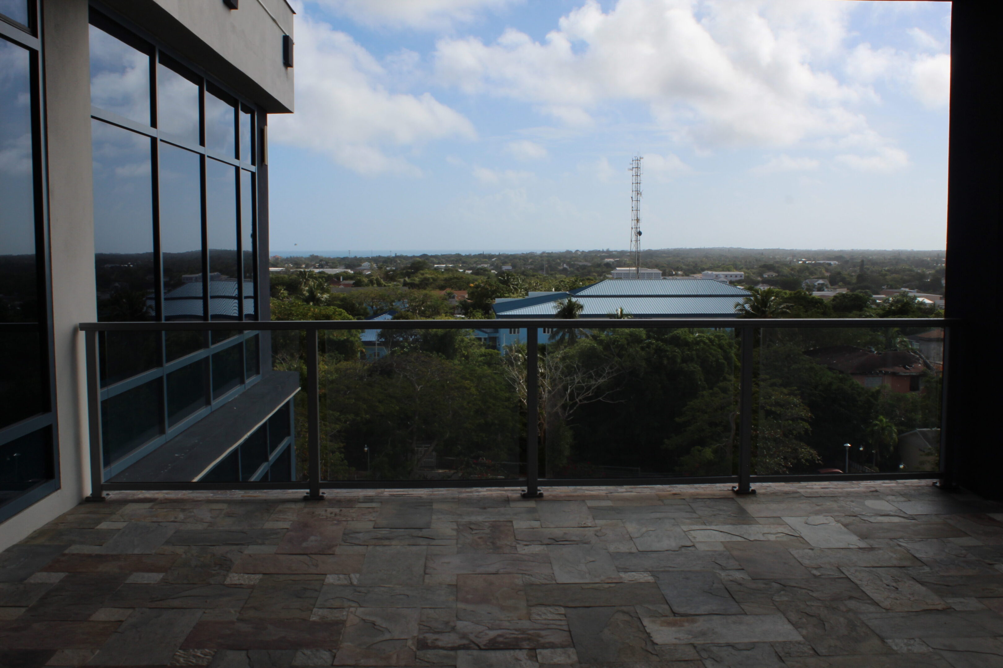 Balcony view overlooking greenery and water under a cloudy sky.