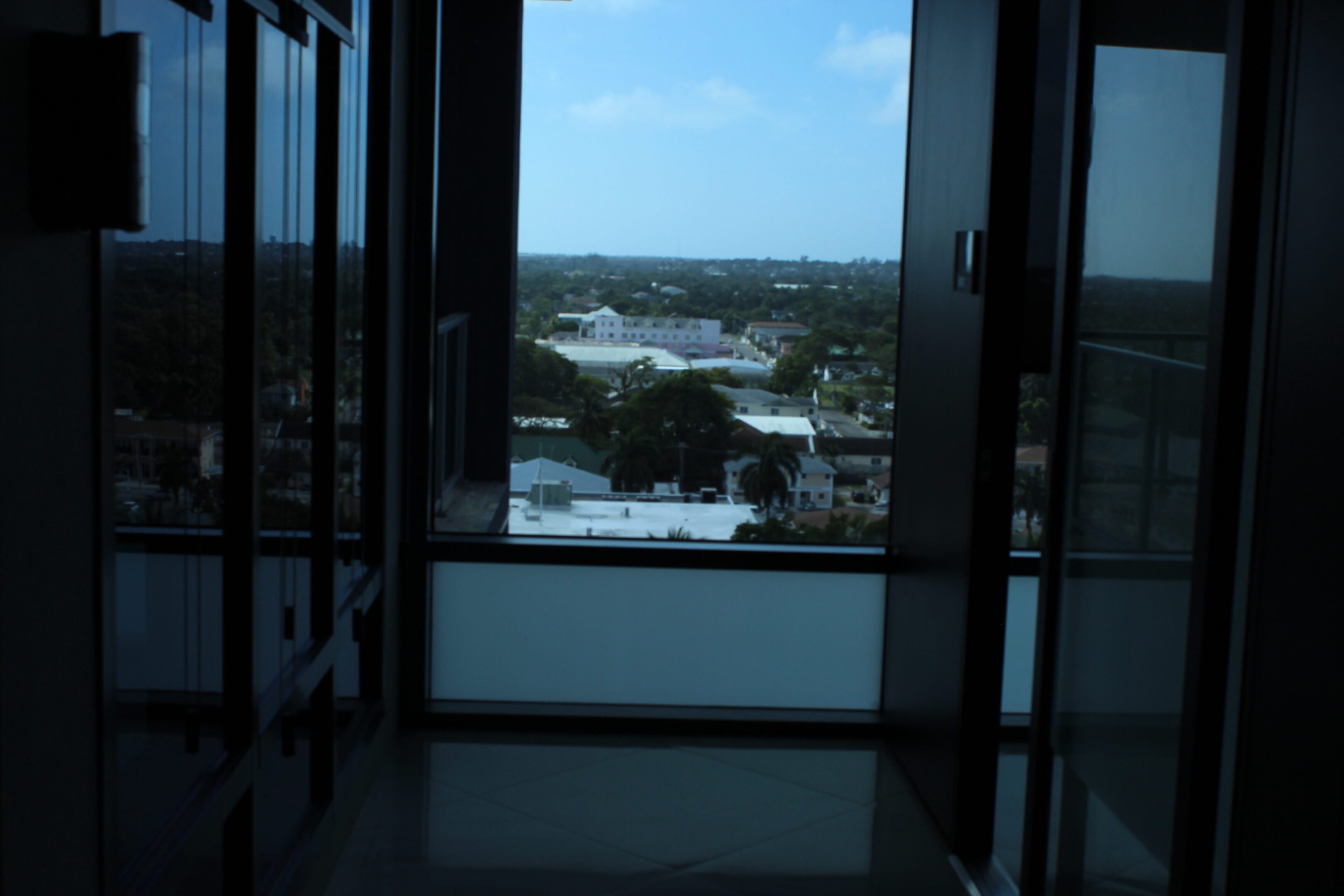View of a cityscape through an open window from a dark room.