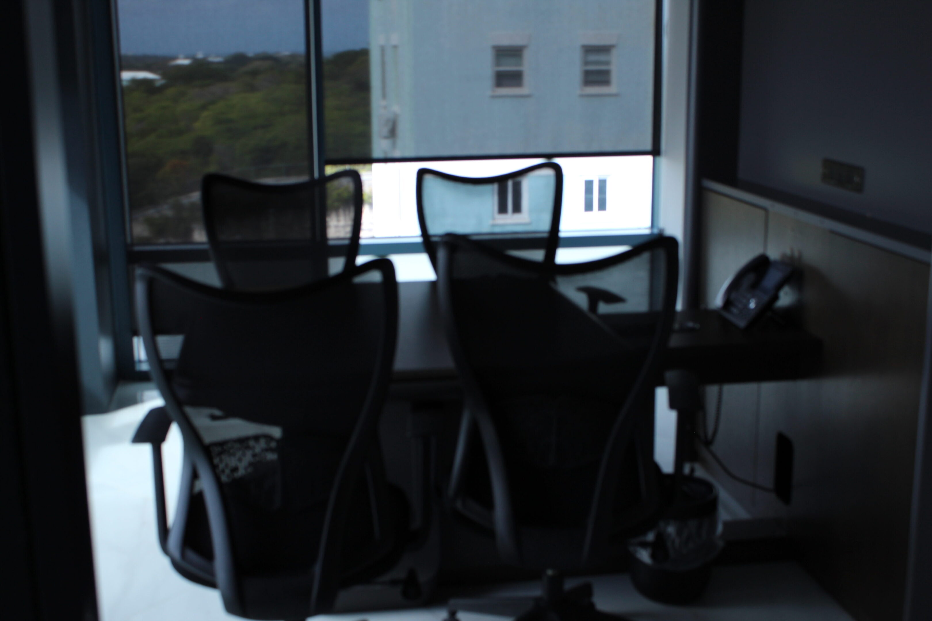 Empty office chairs around a glass table near a window.