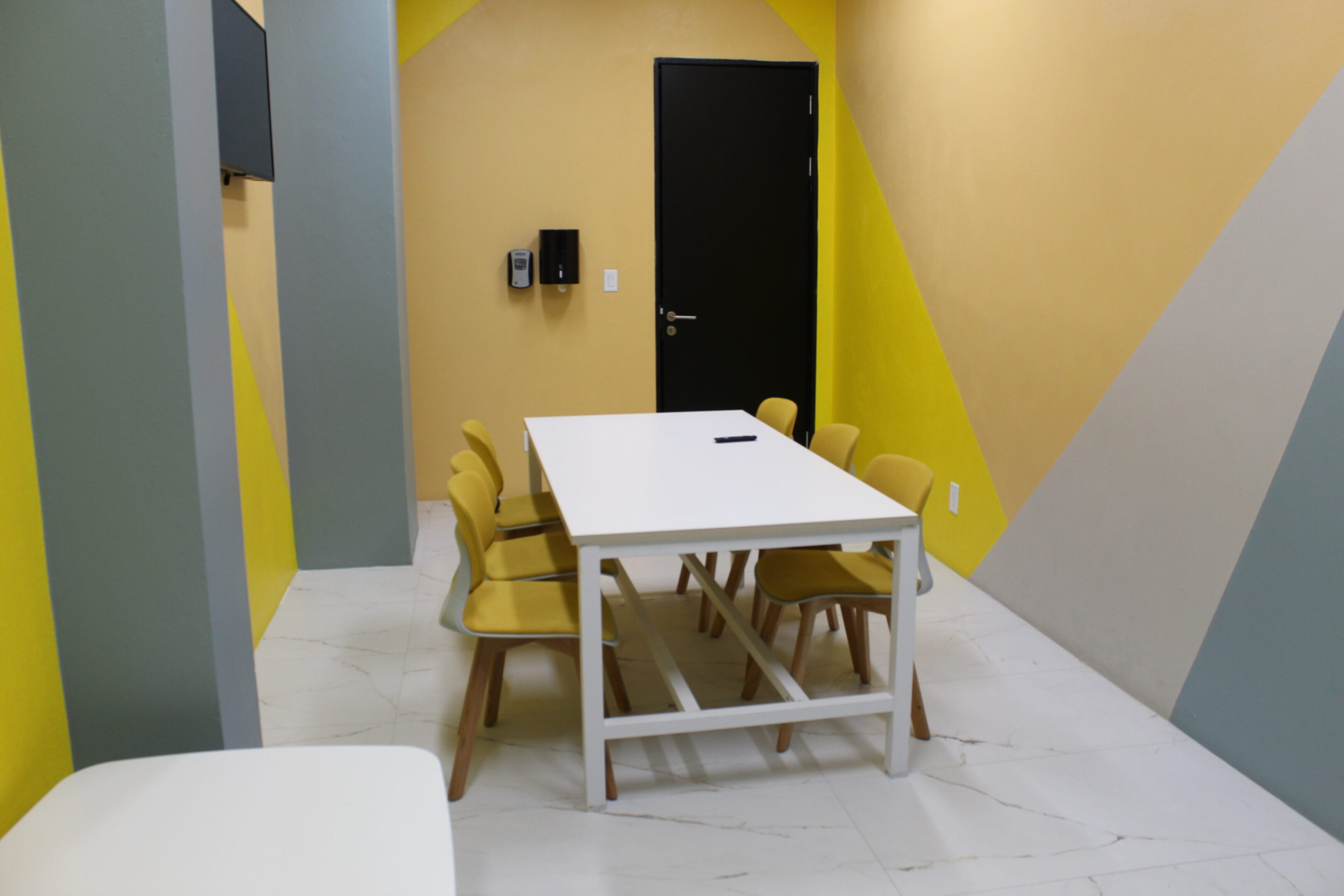 Minimalist meeting room with yellow and gray walls and a white table.