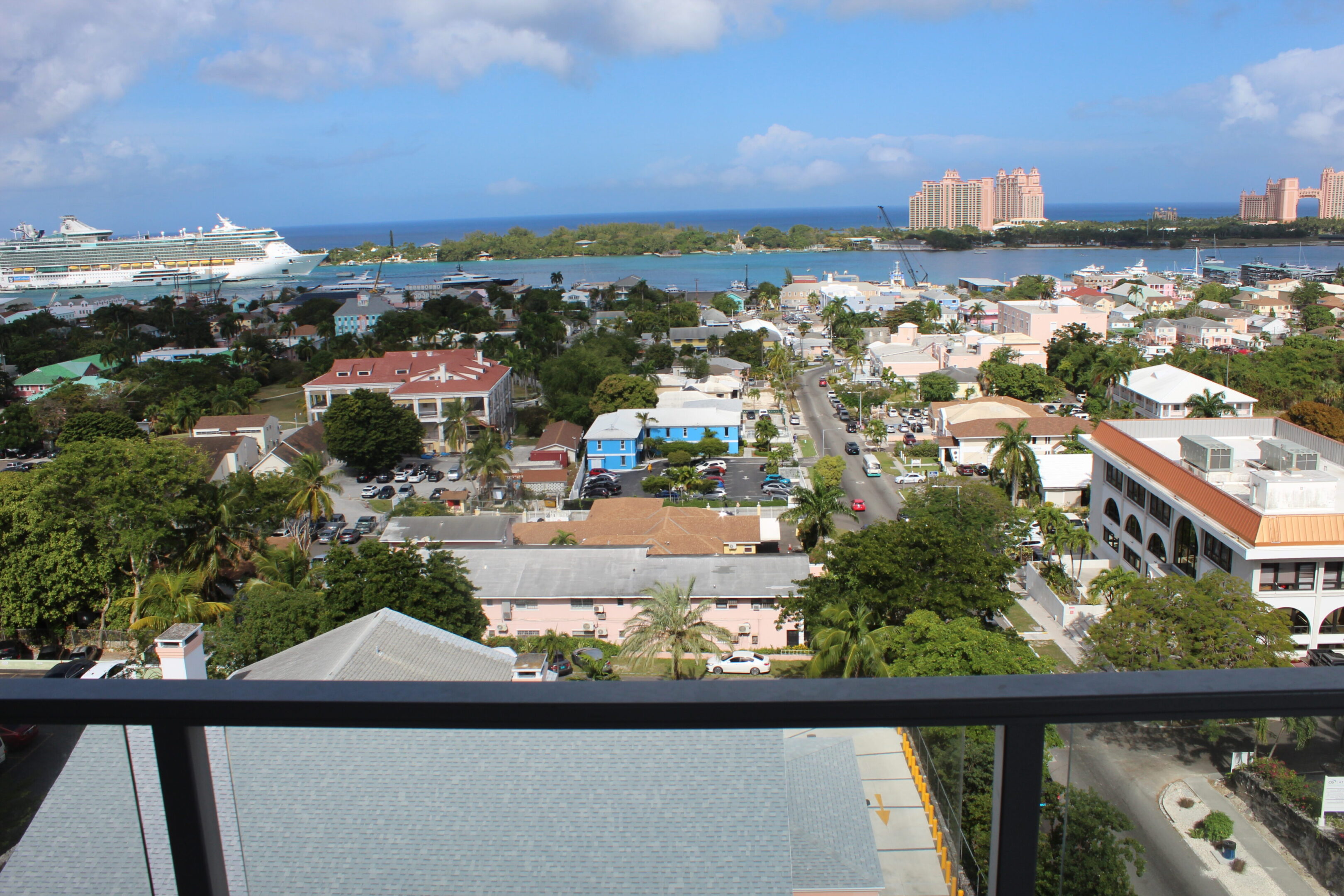 View of a coastal city with buildings, greenery, and the ocean in the background.