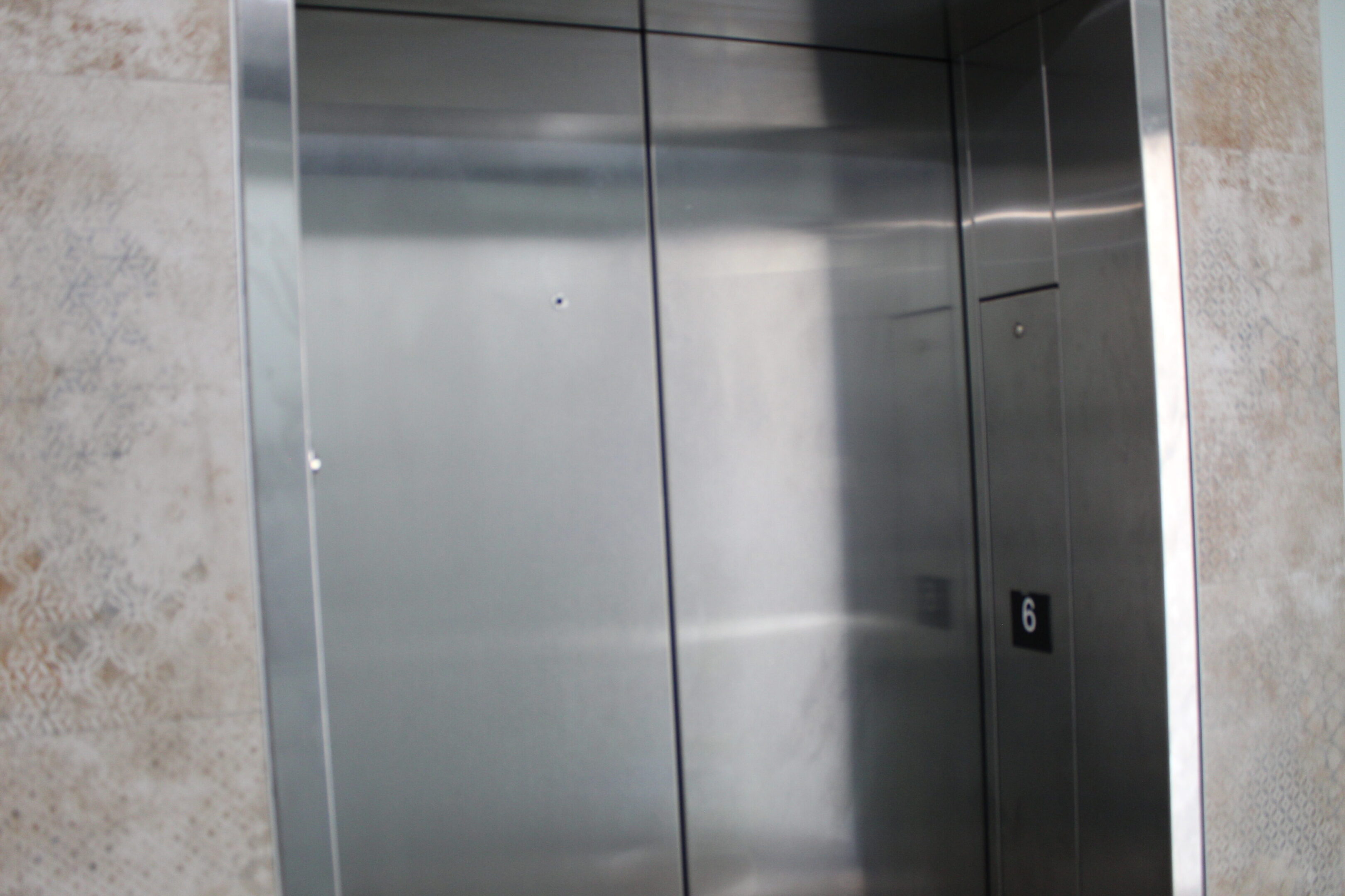Closed stainless steel elevator doors in a modern setting.
