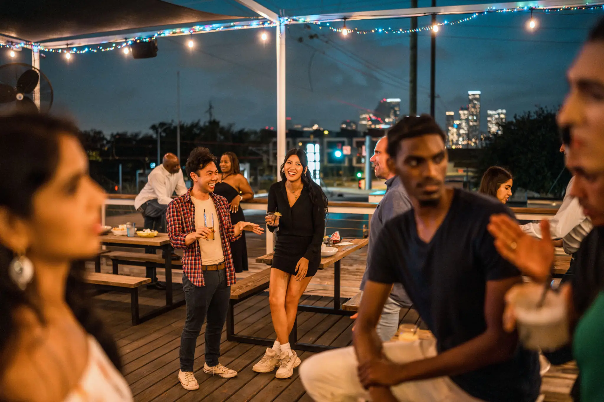 Friends enjoying a rooftop evening with city lights in the background.